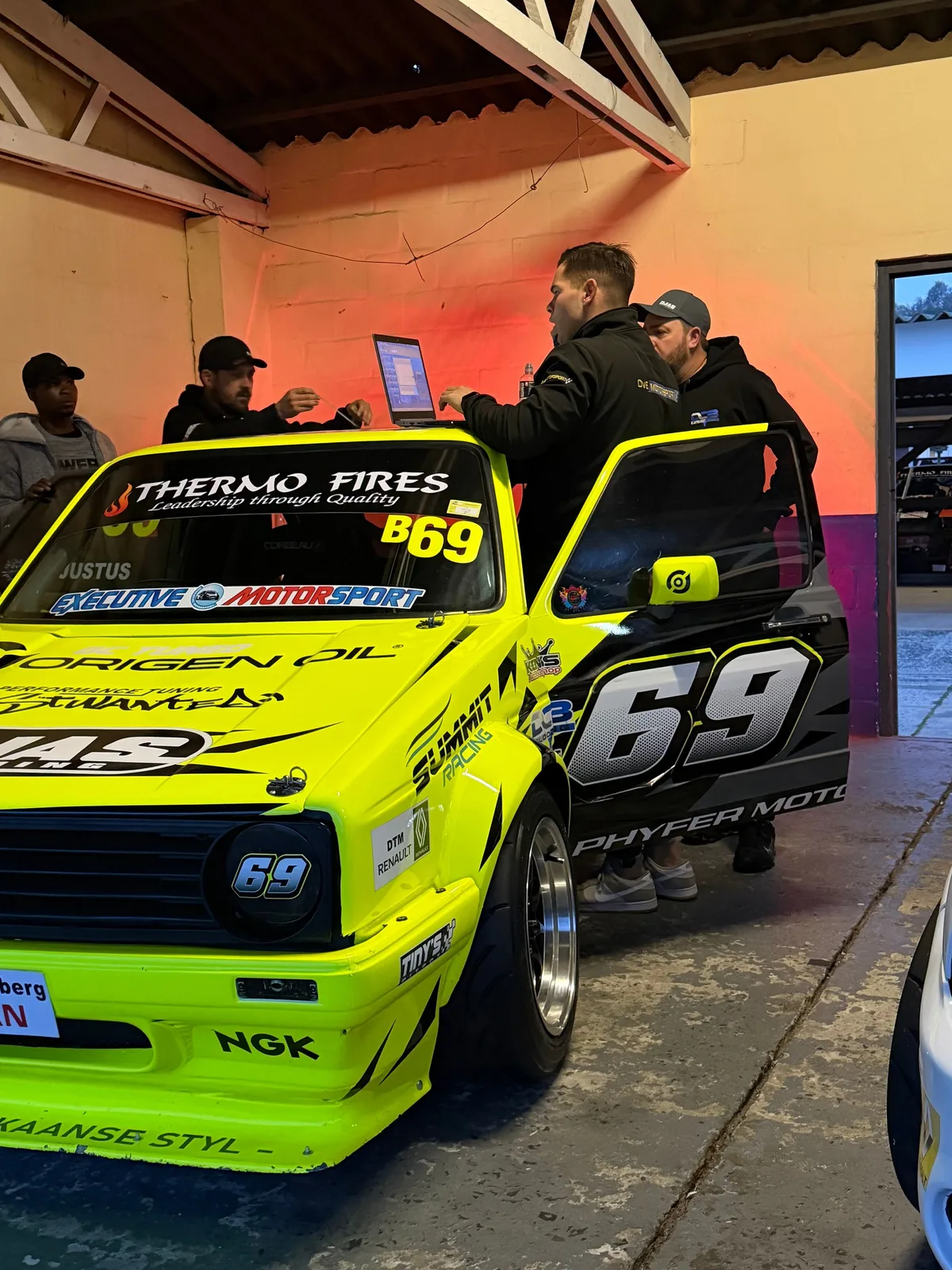 DVE Motorsport team reviewing data beside a race car in the workshop